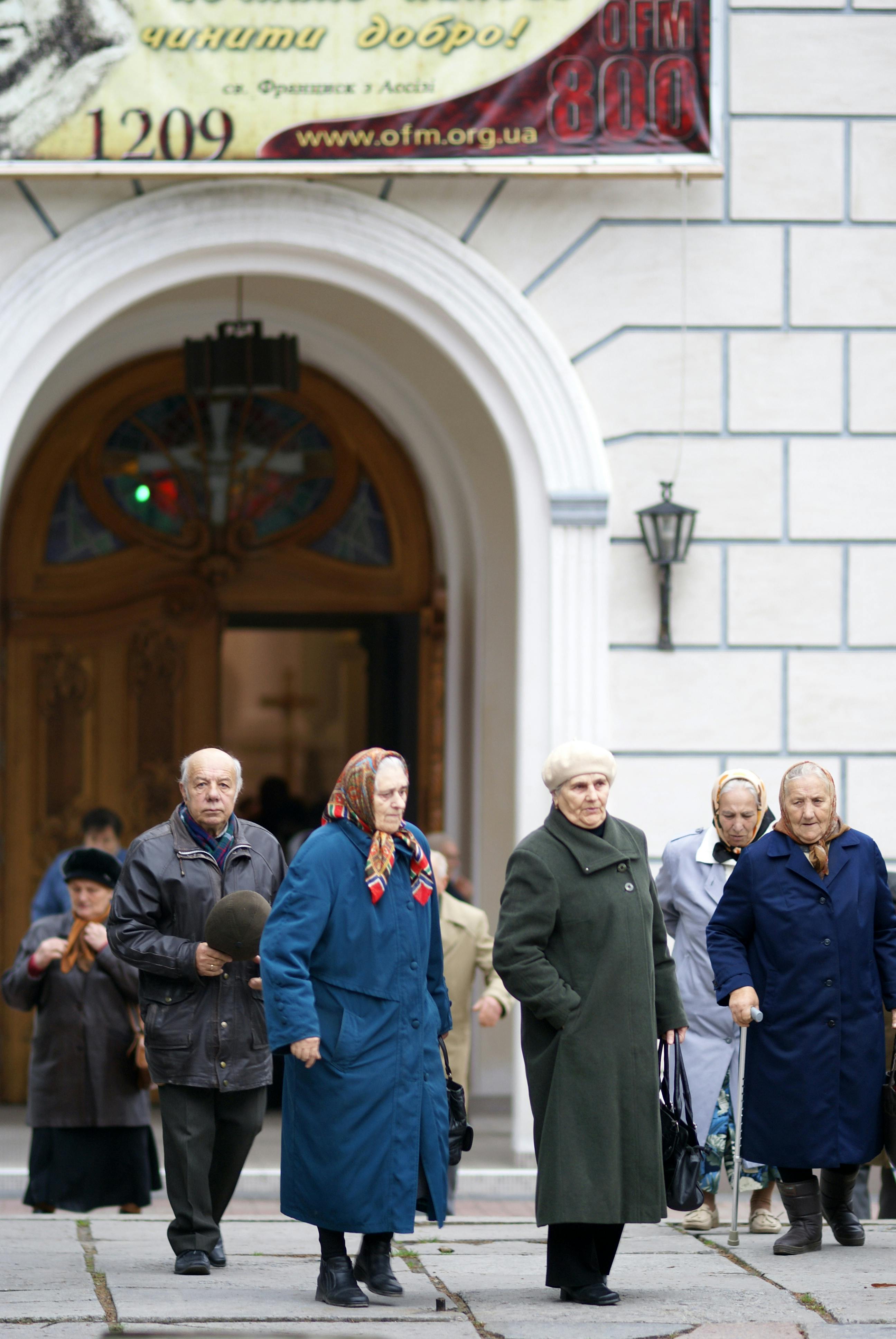 Supporting-you-in-achieving-sec-IMG.jpg A group of elderly people leaving a church in Ukraine during the day.