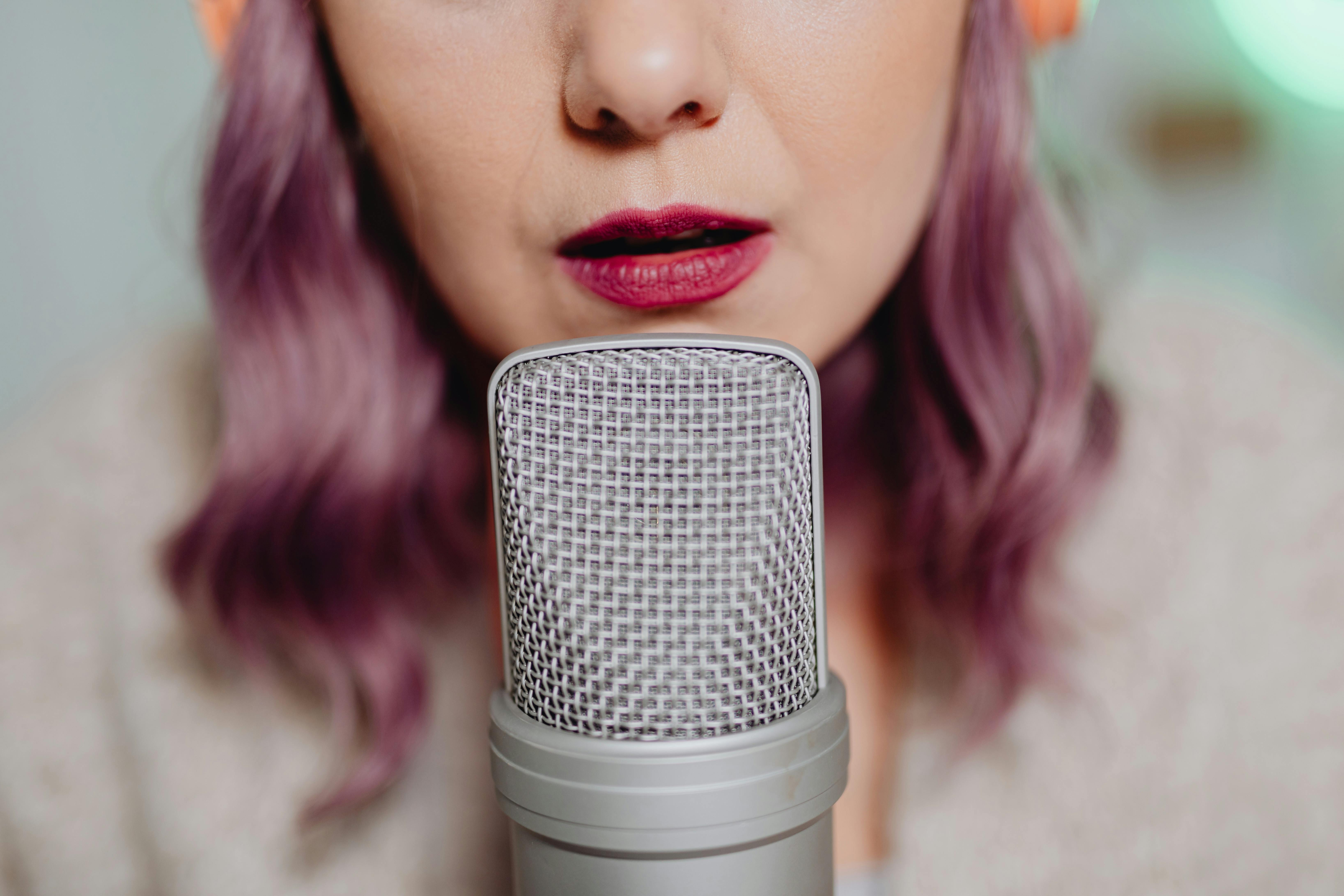 Close-up of a woman with purple hair speaking into a microphone.