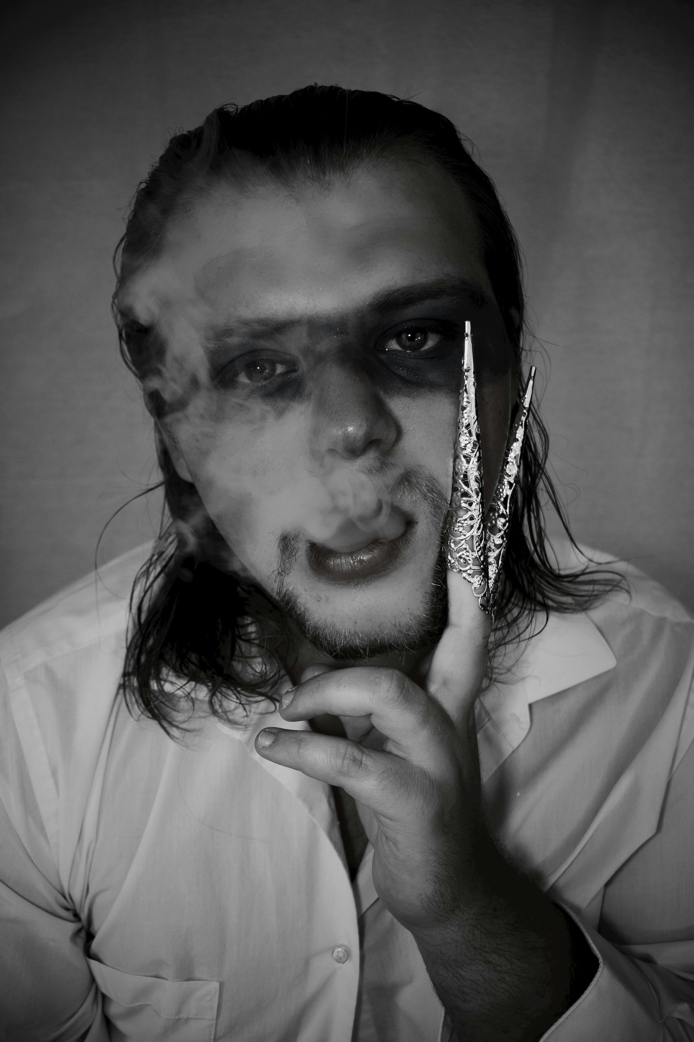 Intriguing black and white portrait of a man with dramatic lighting, smoke, and a contemplative look.