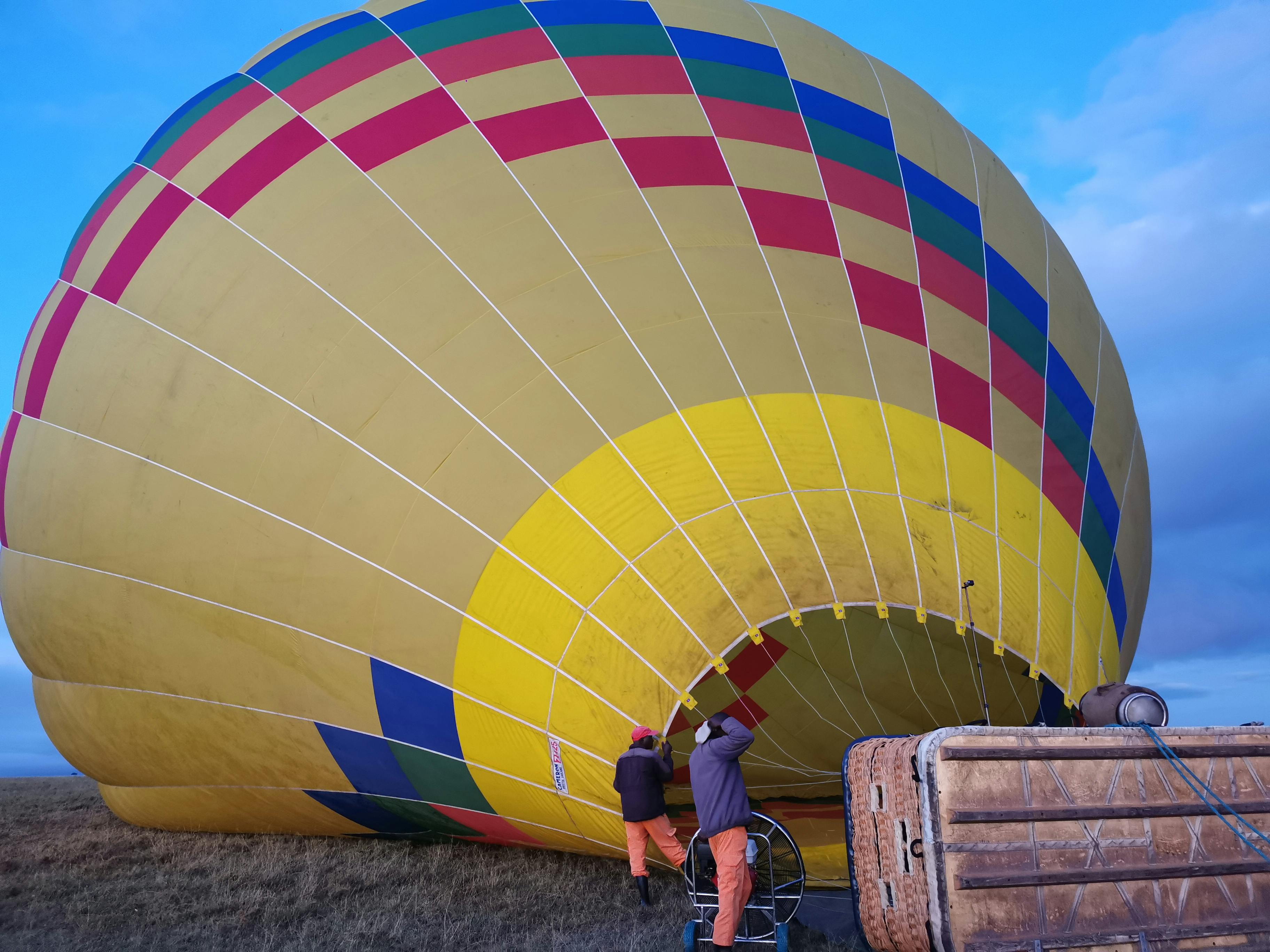 Home A vibrant hot air balloon being set up for an adventure in the Kenyan landscape.