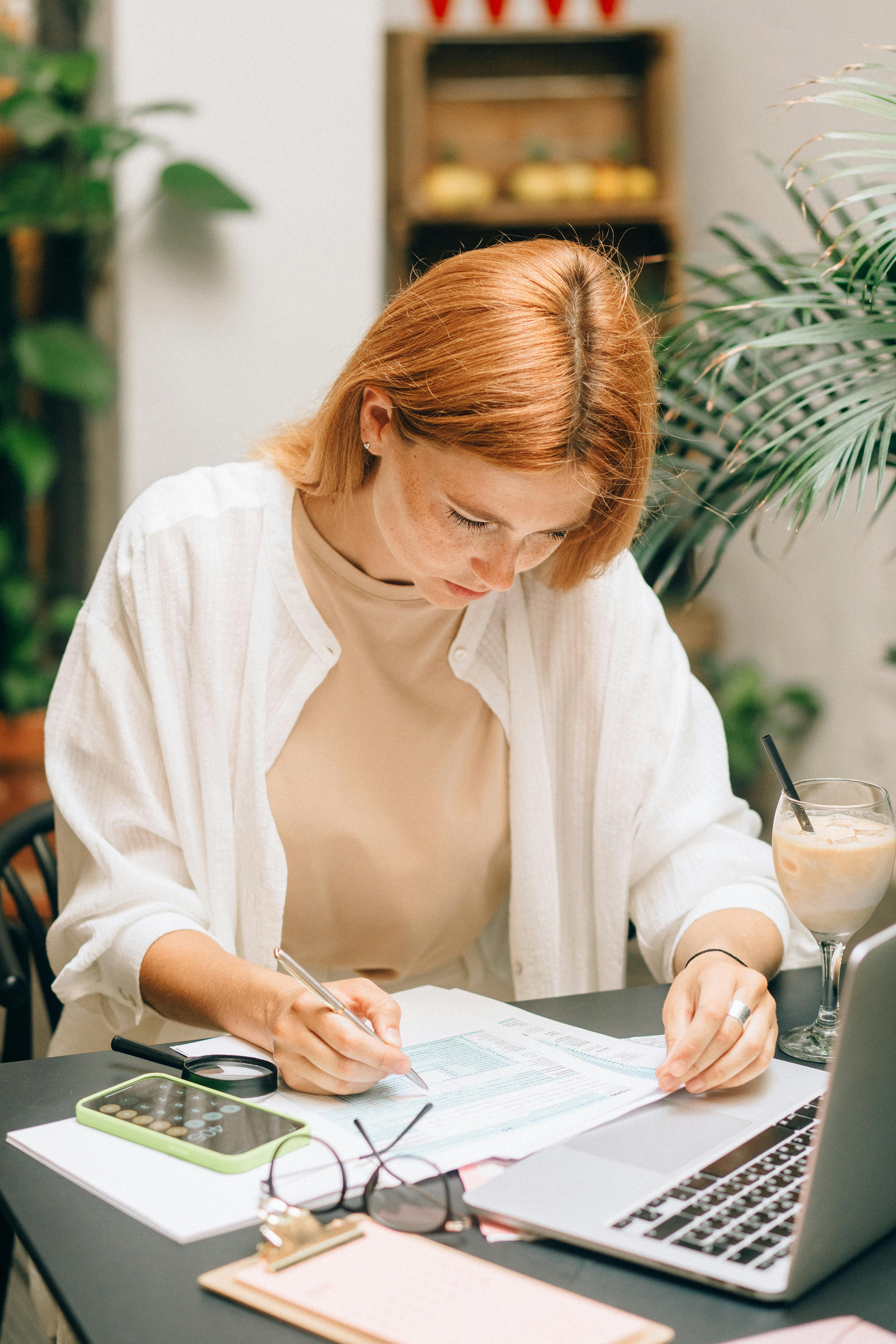 Services Woman analyzing financial documents using laptop and calculator indoors.
