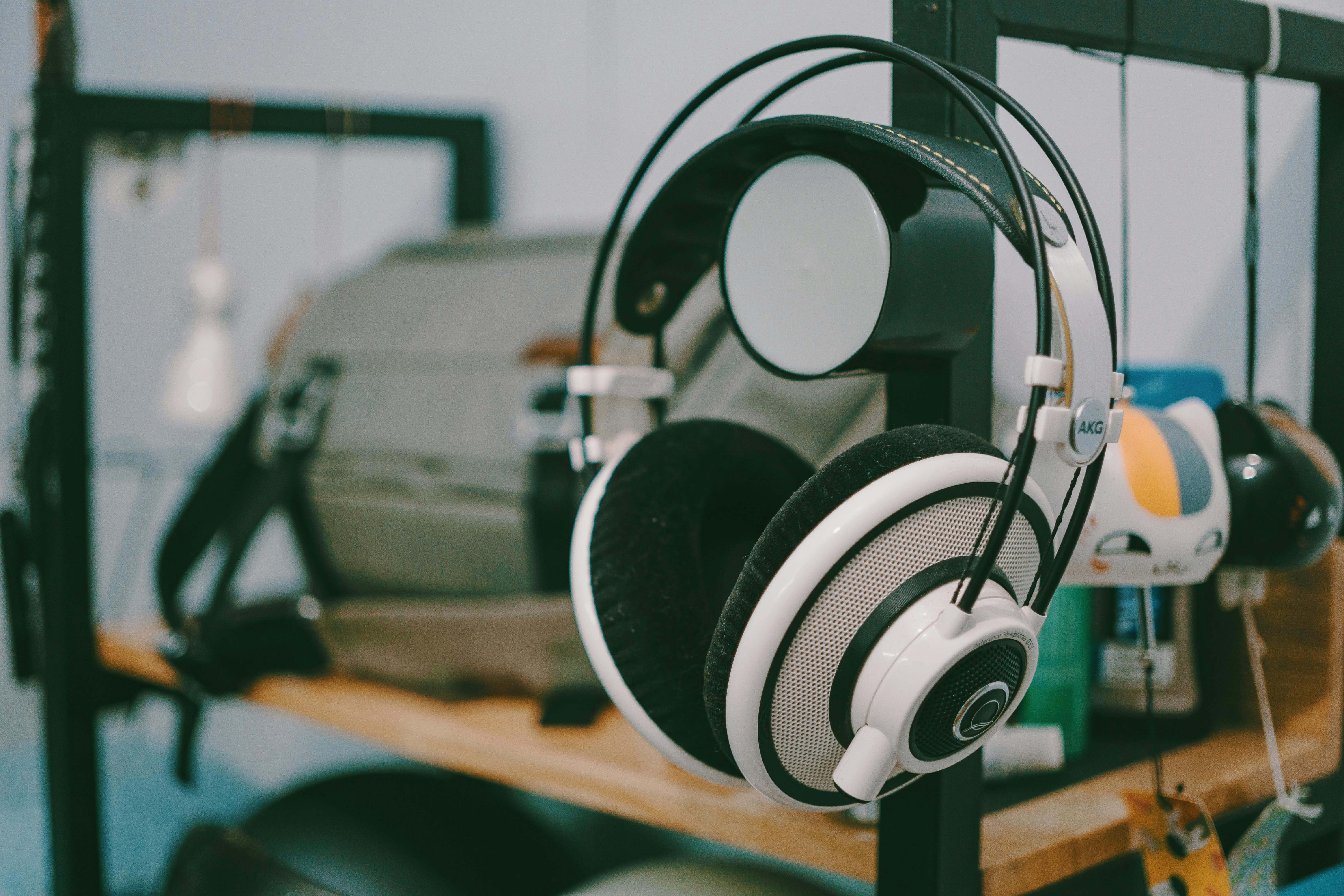 Close-up of AKG headphones hanging on a shelf in an indoor setting.