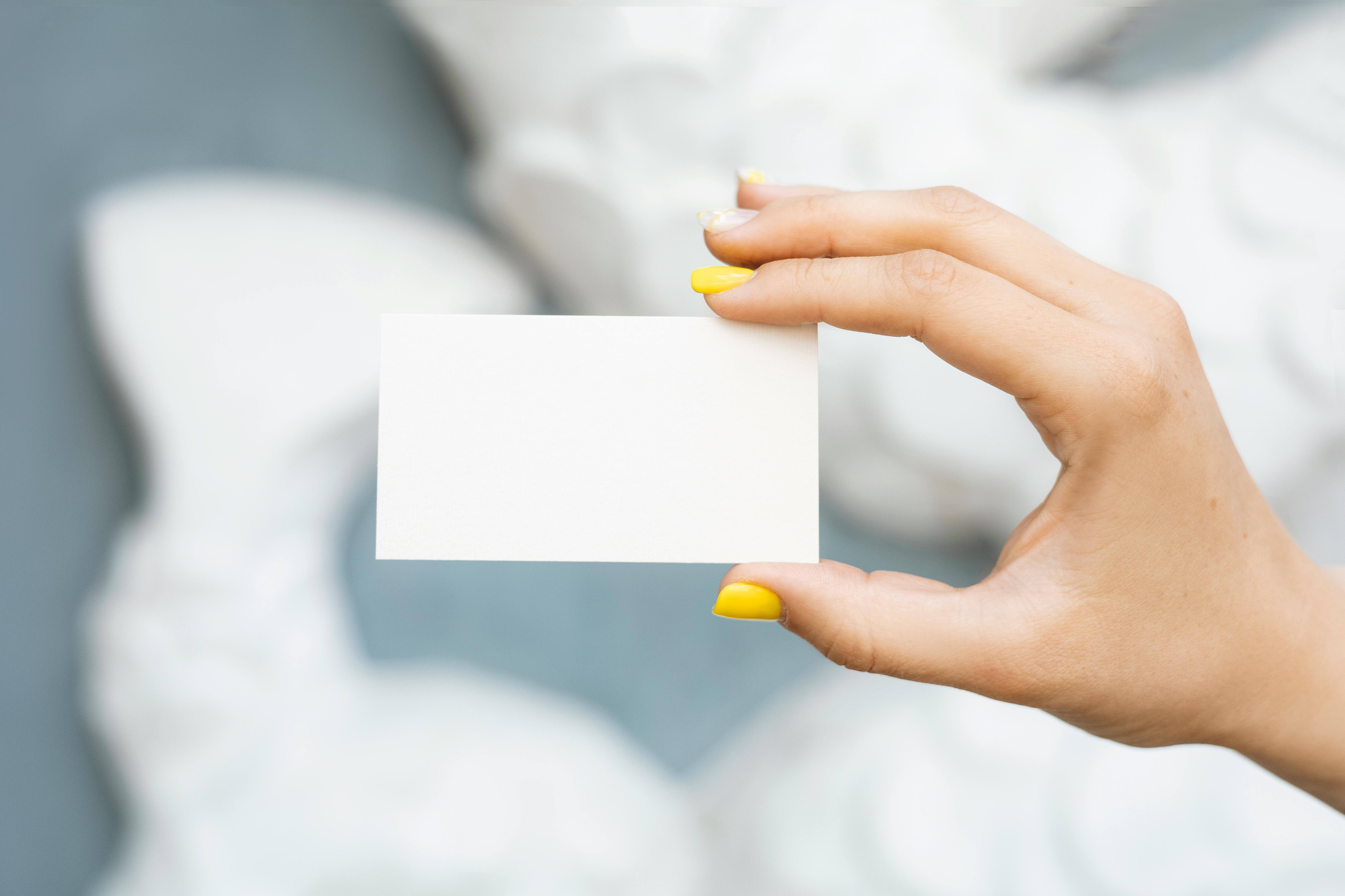 Minimalistic close-up of a hand displaying a blank business card with a blurred background, perfect for mockups.