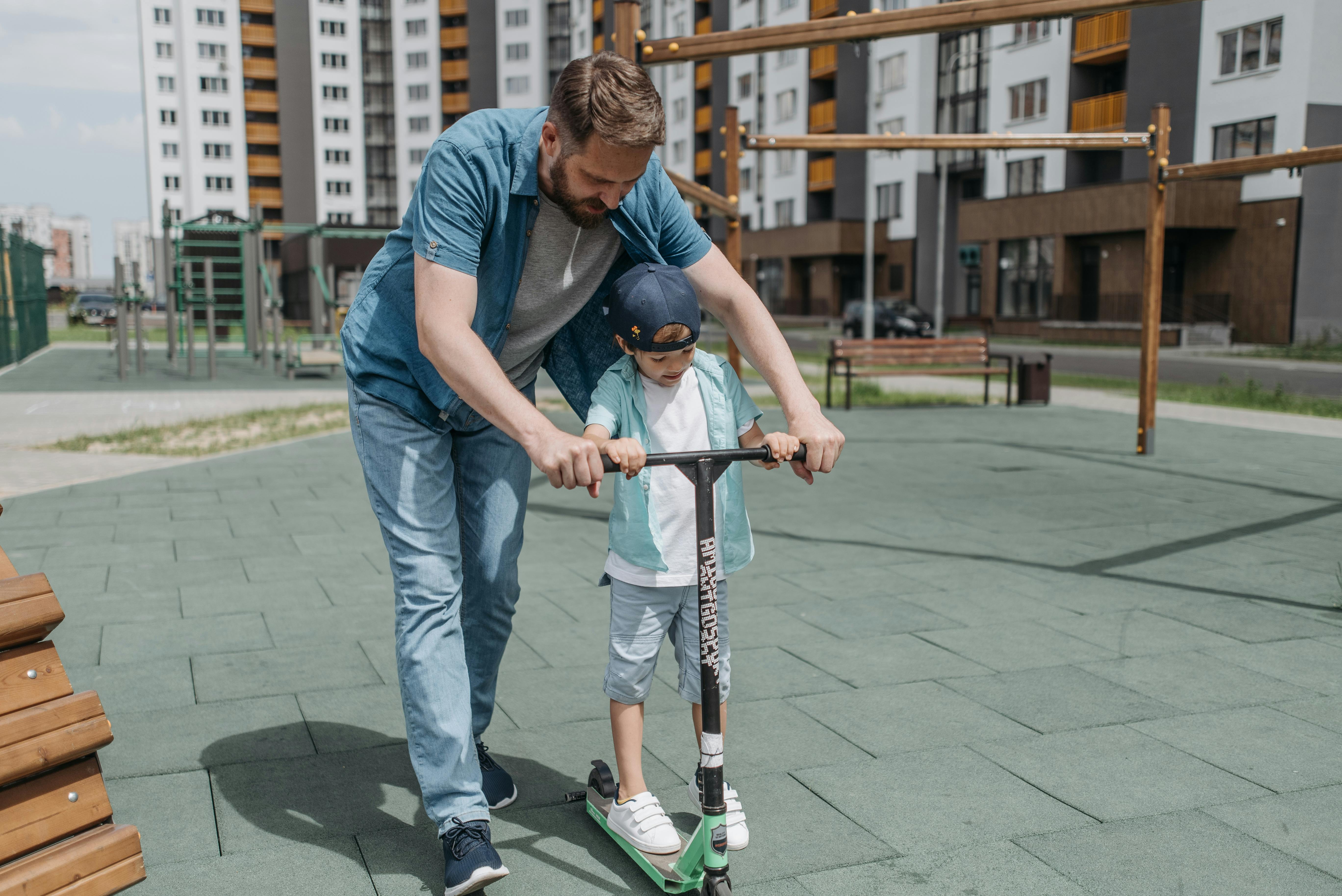 Father and son practicing scooter rides outdoors