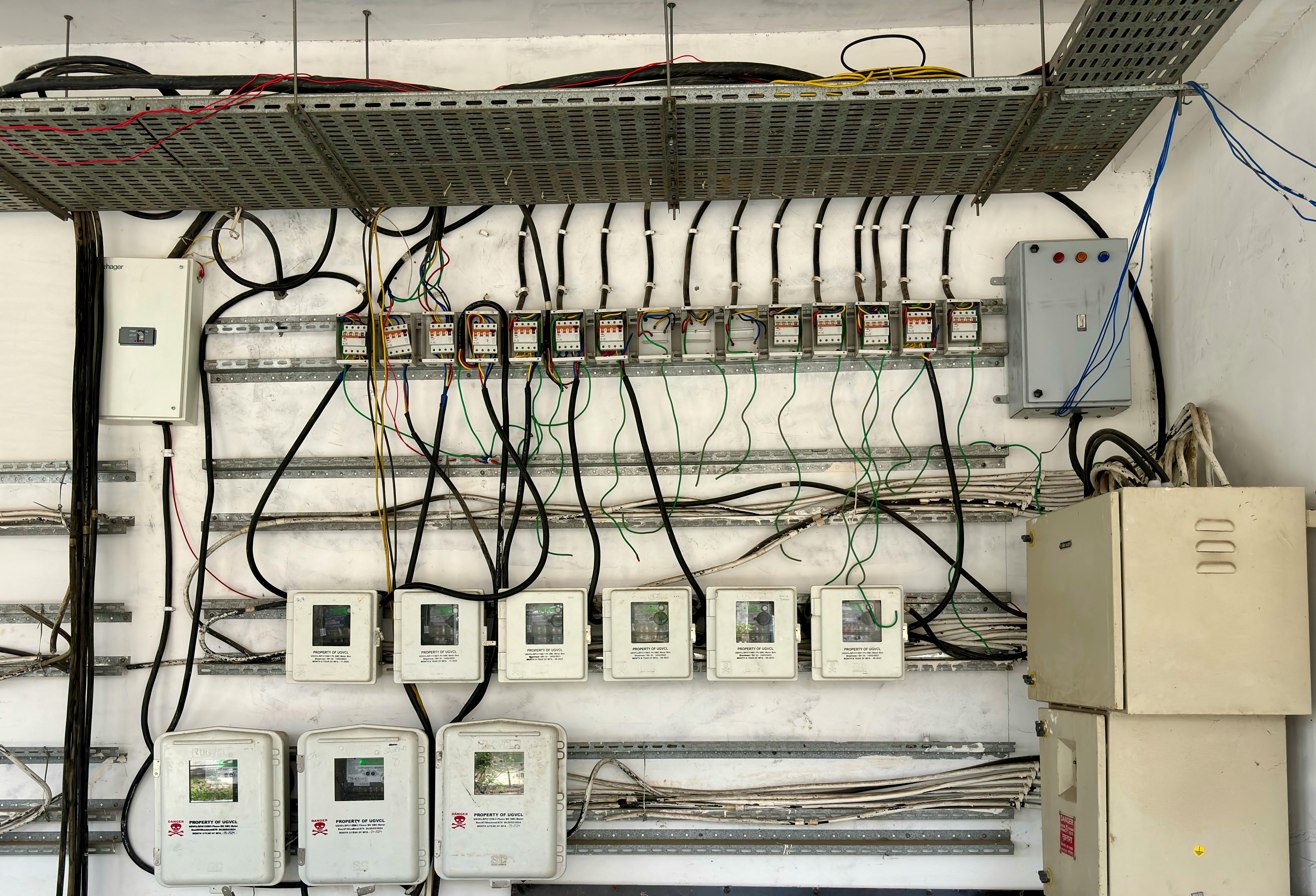 Services Complex network of electrical wiring and control panels in an industrial setting.
