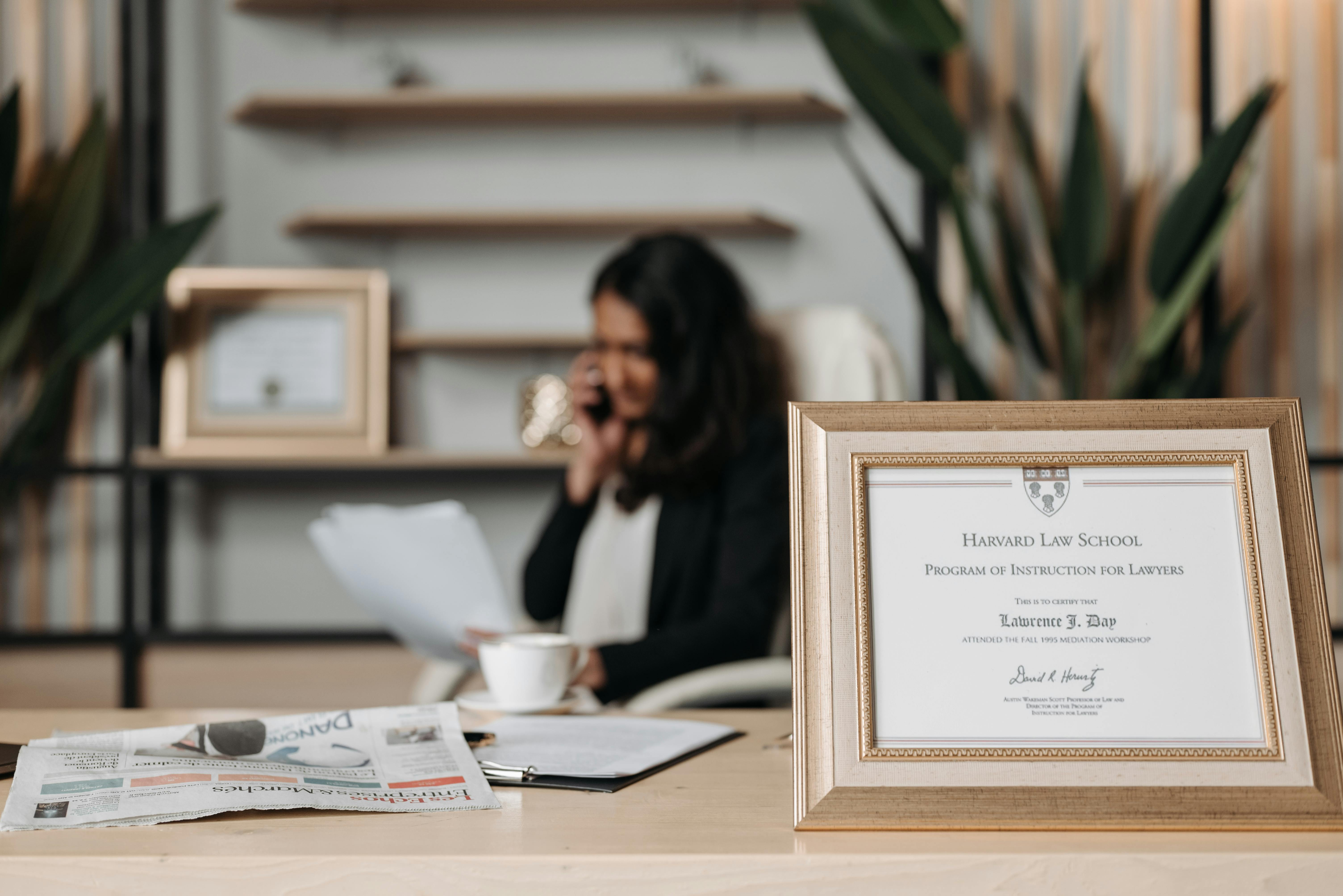 Framed Harvard Law School certificate on desk in elegant office setting.