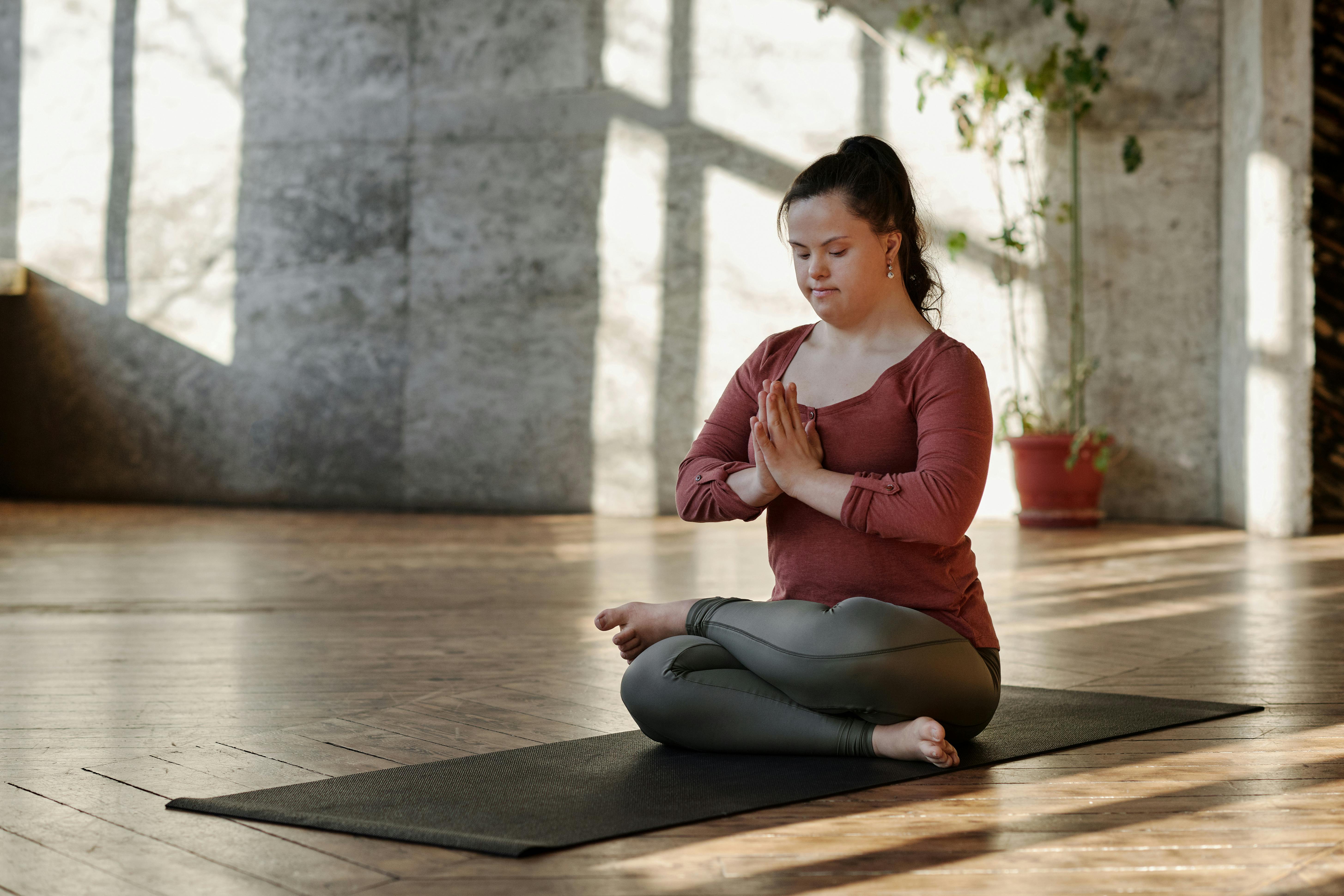 Woman practicing yoga on a mat indoors, finding inner peace and relaxation in a serene setting.