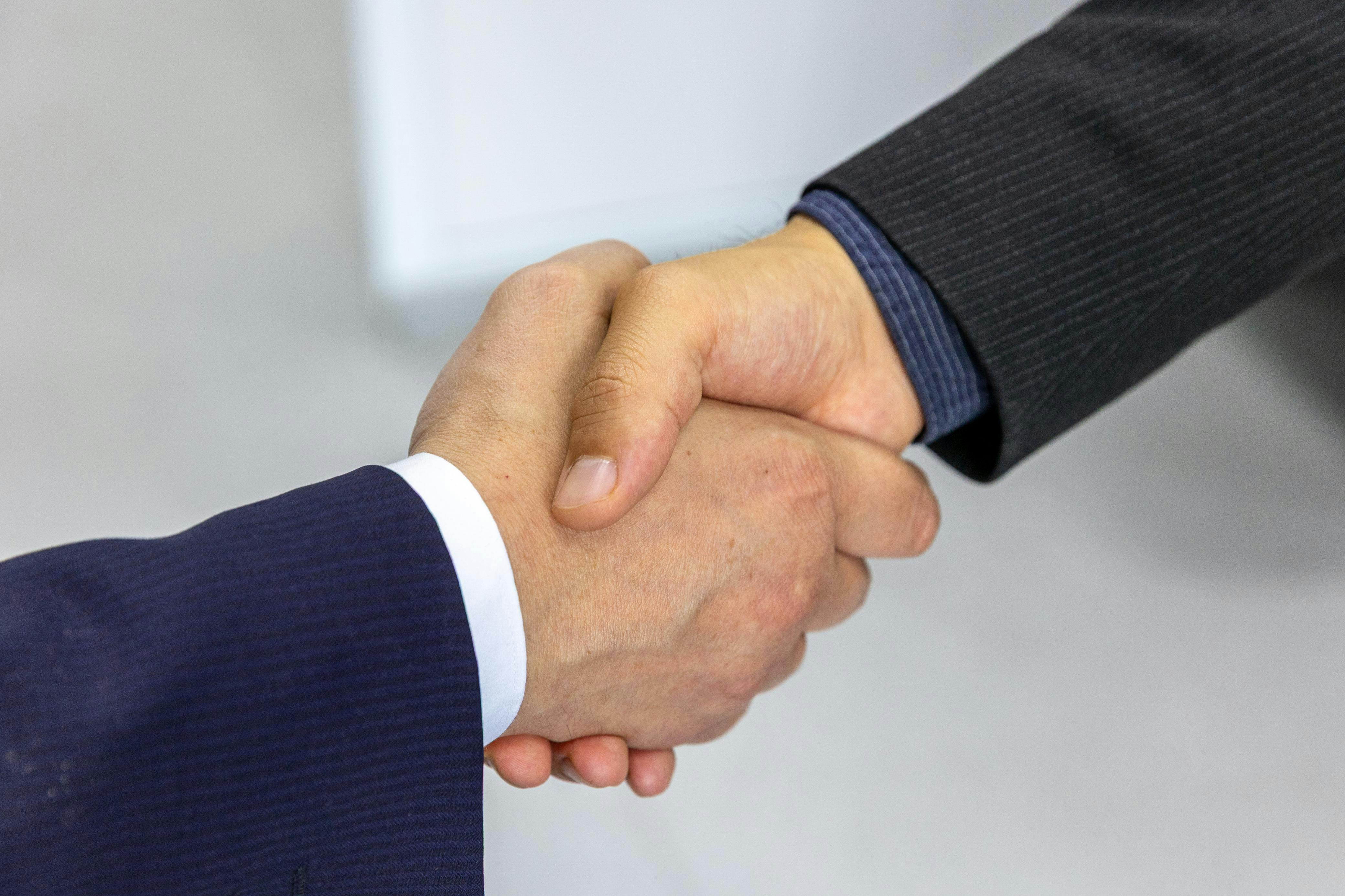 Close-up of two businessmen shaking hands, symbolizing agreement and partnership.